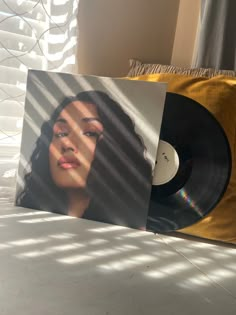 a record player sitting on top of a bed next to a window covered in blinds