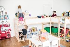 two children are playing in their playroom with wooden furniture and bookshelves on the wall