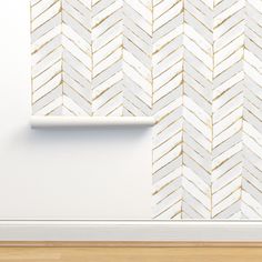 an empty room with a white wall and gold painted chevron pattern on the wall