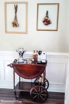 a small cart with items on it in front of two framed pictures