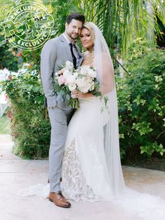 a bride and groom pose for a photo in front of some greenery at their wedding