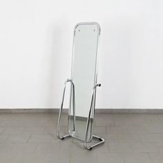 a standing mirror on the floor in front of a white wall