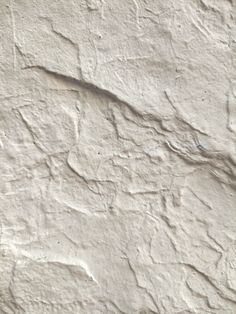 an old white stucco wall with cracks in it