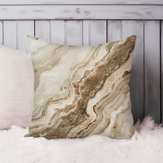 a white and gold pillow sitting on top of a fur covered bed