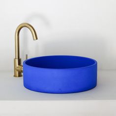 a gold faucet sits next to a blue bowl on a white countertop