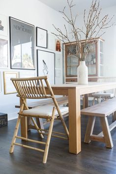 a wooden table with two chairs and a vase filled with flowers sitting on top of it