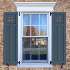 an open window with blue shutters in front of a brick wall and stone building