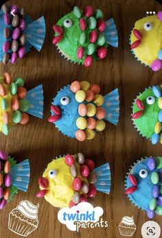 cupcakes decorated to look like fish on a wooden table with candy candies