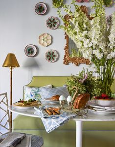 a table topped with plates and flowers on top of a white table covered in dishes