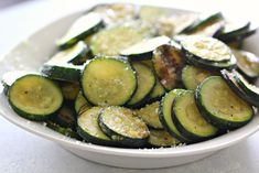 a white bowl filled with sliced cucumbers on top of a table