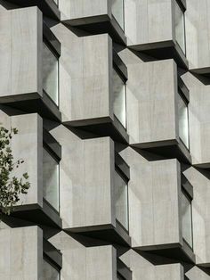 the side of a building with concrete blocks on it and a tree in front of it