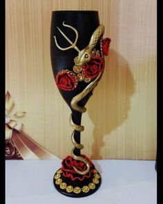 a black and gold goblet with red roses on it