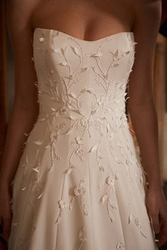 the back of a woman's wedding dress with floral appliques on it