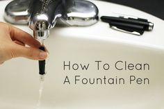 a person is filling their fountain pen with water from the faucet that they are holding