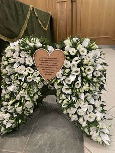 a heart shaped wreath with white flowers and a poem written on the front is surrounded by greenery