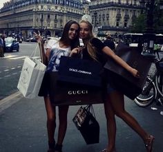 two beautiful young women standing next to each other holding shopping bags