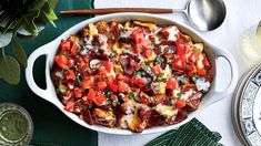 a casserole dish with tomatoes and cheese in it on a green table cloth