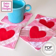 three coasters with hearts on them sitting next to a blue cup and saucer