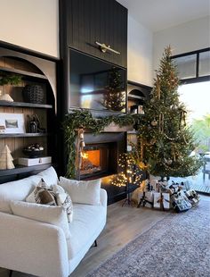 a living room filled with furniture and a christmas tree in front of a fire place