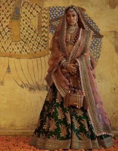 a woman dressed in an elaborately designed outfit and headpiece, standing next to a wall