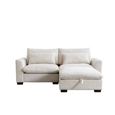 a white sectional couch with pillows on the back and foot rest in front of it