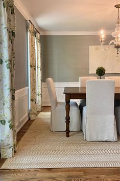 a dining room table with white chairs and a chandelier hanging from the ceiling