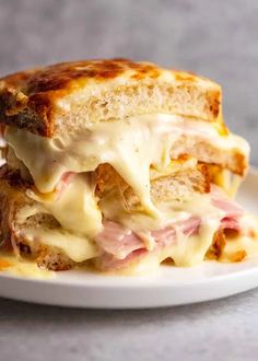 a white plate topped with a cut in half sandwich covered in cheese and meats