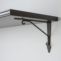 a shelf with two brackets on it and a metal bar hanging from the wall behind it