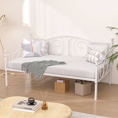 a white day bed sitting on top of a hard wood floor next to a potted plant