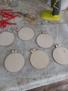 six unfinished wooden circles sitting on top of a table next to scissors and pliers