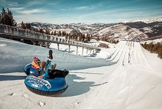 a man riding on top of an inflatable tube down a snow covered slope