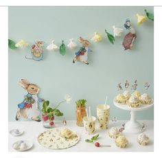 a table topped with cakes and cupcakes covered in frosting next to bunting