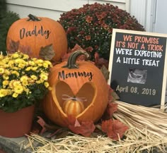 two pumpkins sitting next to each other in front of a sign that says daddy, it's not a trick we're expecting a little treat