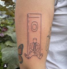 a man with a tattoo on his arm sitting in front of a toilet paper dispenser