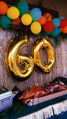 a table topped with balloons next to a large number 60 sign and a roasting pan