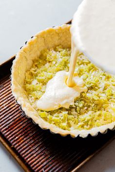 a person pouring batter into a pie crust on top of a pan filled with food