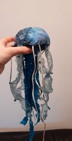 a hand holding an object that looks like a jellyfish with blue and white paint on it