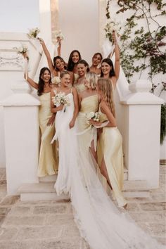 a group of women standing next to each other in front of a white wall with flowers