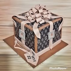 a cake that looks like a louis vuitton suitcase with a bow on top