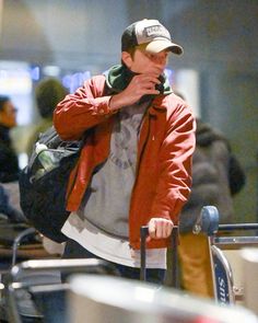 a man in a red jacket and hat is walking through an airport