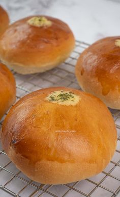 four round breads cooling on a wire rack with yellow mustard sprinkled on them