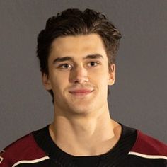 a young man wearing a jersey posing for a photo in front of a gray background