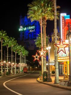 palm trees line the street at night in front of a hotel and casino with neon lights