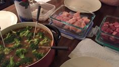 a person sitting at a table with food in bowls and plates on it, including broccoli