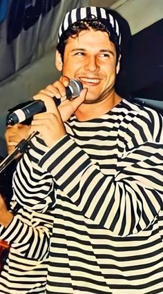 a man in striped shirt singing into a microphone