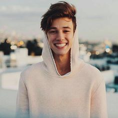 a young man wearing a hoodie smiling at the camera