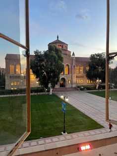 the view from inside an open window looking at a large building with a clock tower