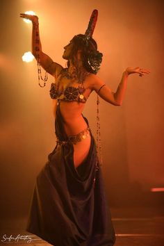 a belly dancer is performing on stage with her hands in the air