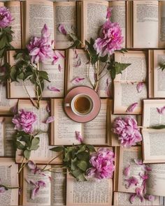 an arrangement of books with pink flowers on them and a cup of coffee in the middle