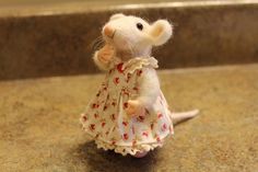 a small toy mouse in a dress on a counter